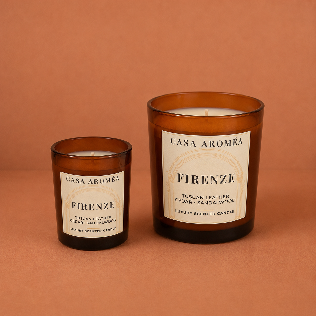 Firenze Small and Large scented candles by Casa Aroméa in amber glass vessels against a warm terracotta and cocoa-toned textured background