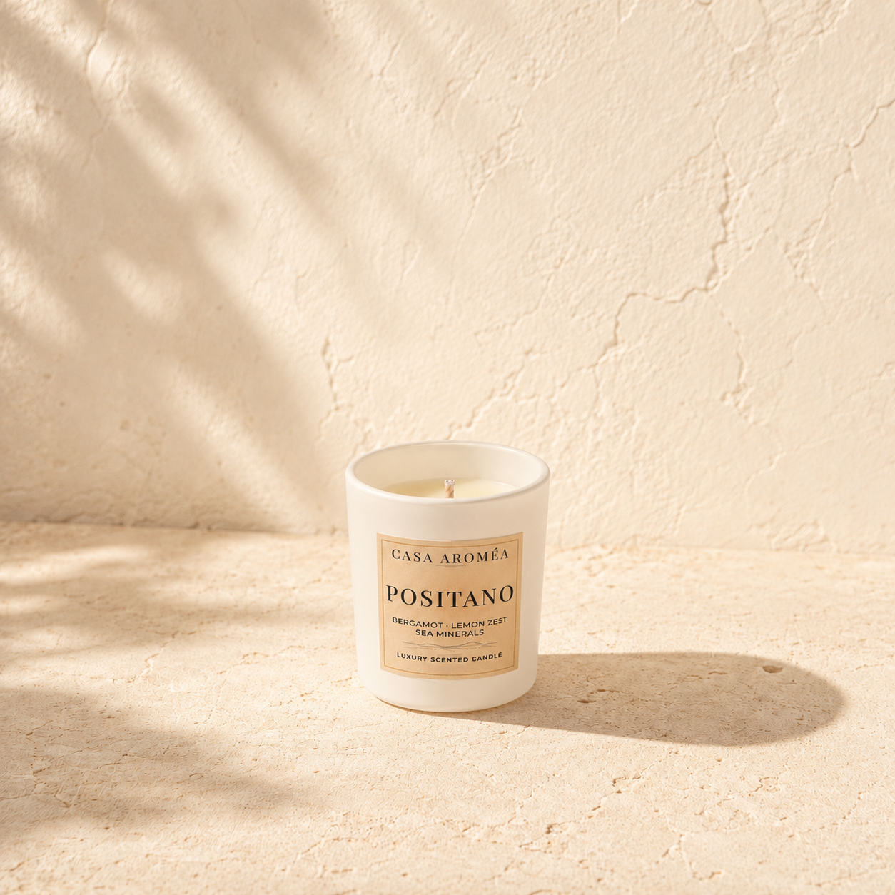 Small Positano scented candle by Casa Aroméa in a white glass vessel against a warm Mediterranean-inspired textured background