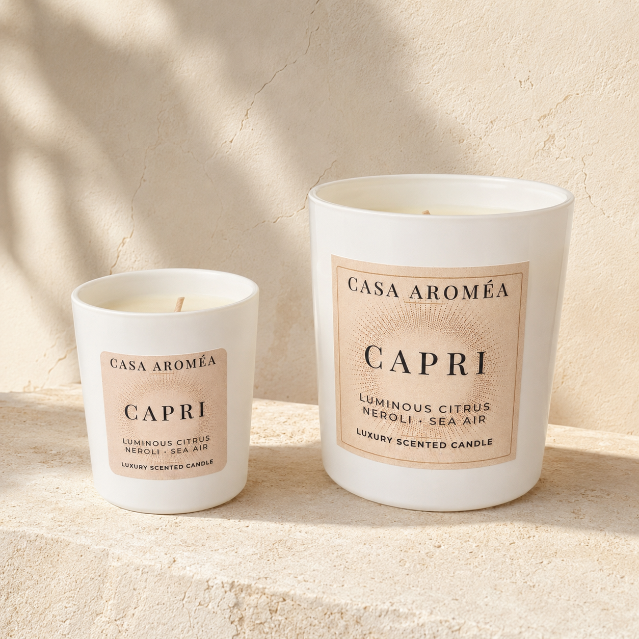Capri Small and Large scented candles by Casa Aroméa in white glass vessels against a warm Mediterranean-inspired textured background