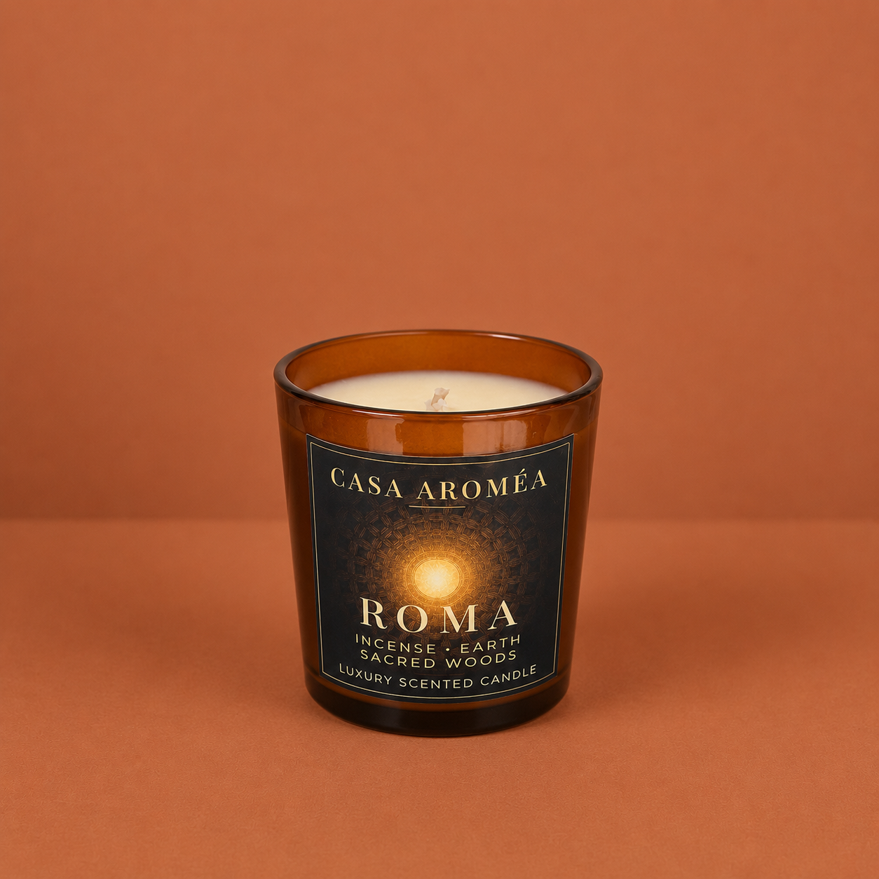 Small Roma scented candle by Casa Aroméa in an amber glass vessel against a warm terracotta and cocoa-toned textured background